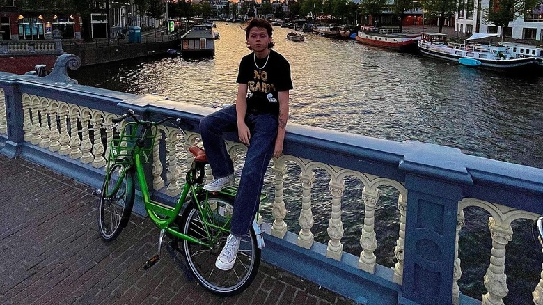 Jacob Sartorius sitting on a wall behind a bike in Amsterdam