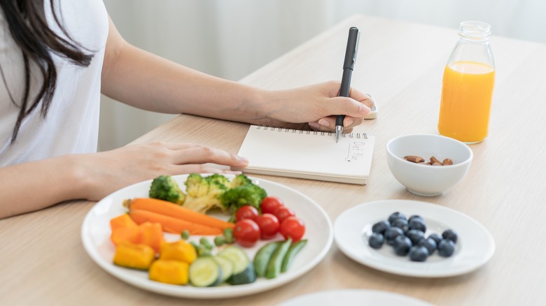 dieter with food writing down meal plan