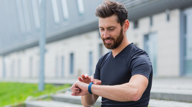 man exercising outdoors checking fitness tracker