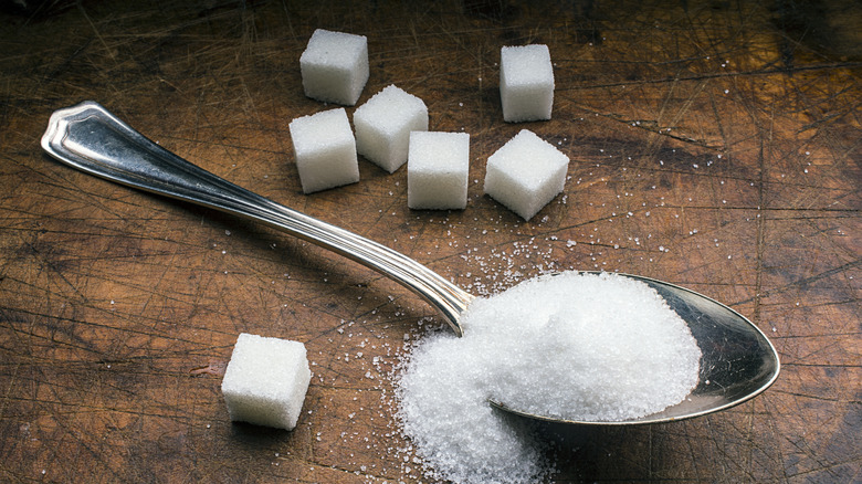 A spoonful of sugar next to sugar cubes