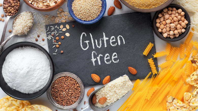 The words "Gluten free" written on a chalkboard surrounded by foods like grains, chickpeas, rice, and pastas.