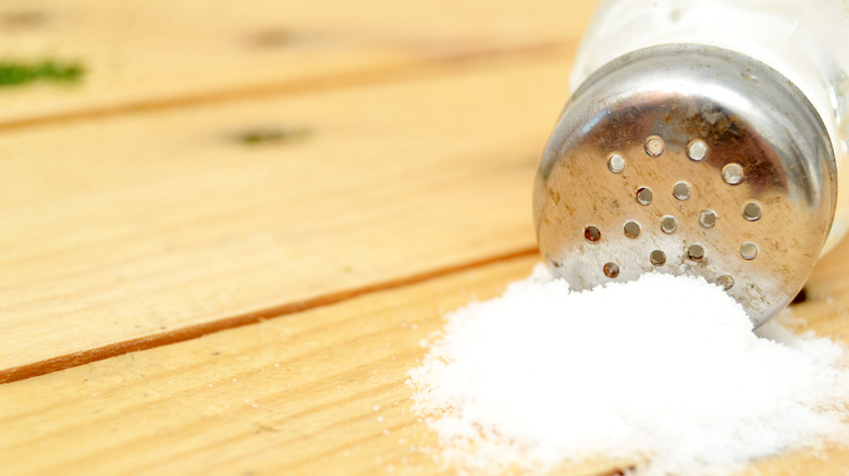 Salt shaker spilled out on a wooden surface