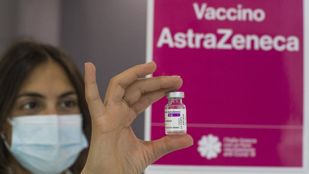 Researcher holds up the AstraZeneca vaccine