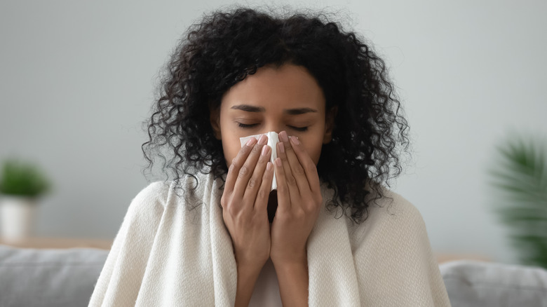 woman sneezing into tissue