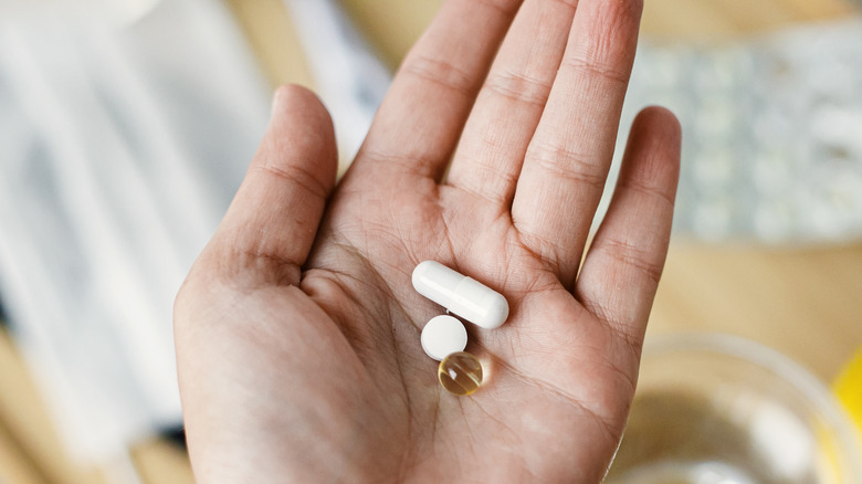 Hand holding various supplements