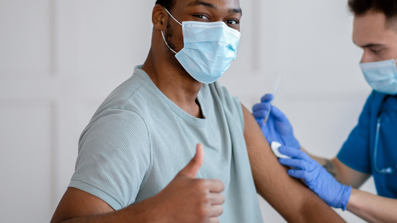 man getting vaccine giving thumbs up