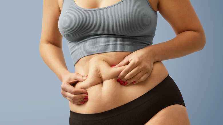 woman pinching fat on stomach