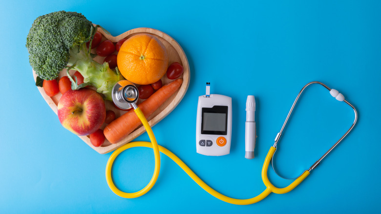 heart-shaped bowl of fruit and vegetables with blood glucose monitor