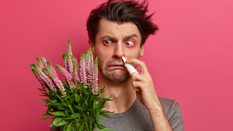 man holding flowers and suffering from hay fever