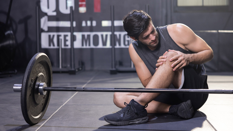 man grabbing knee in gym