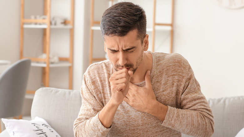 A person coughing and sitting down