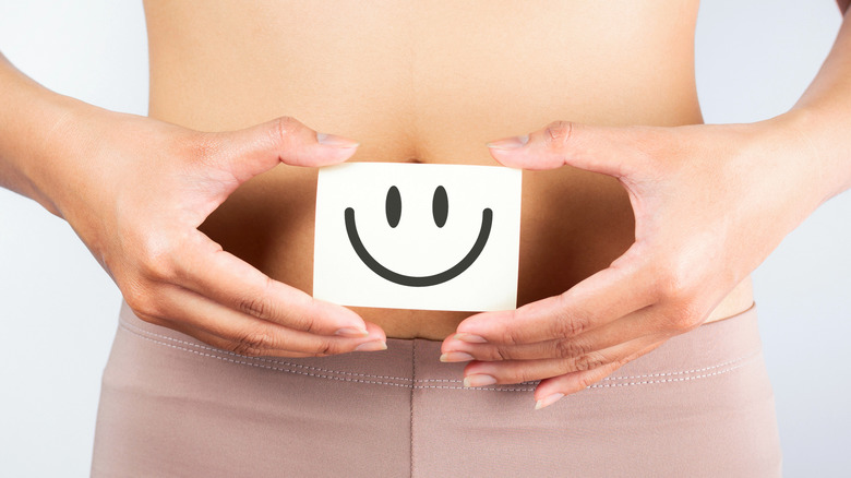 woman holding smiley face over abdomen