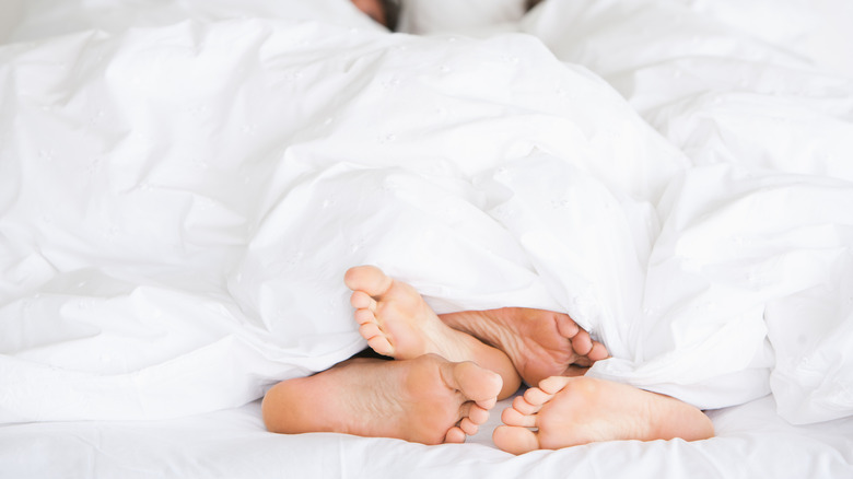 couple's feet peeking from under covers