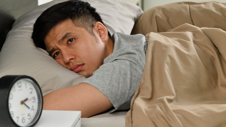 Asian man lying awake in bed in the middle of the night
