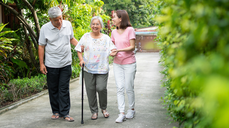 woman using cane walking with family