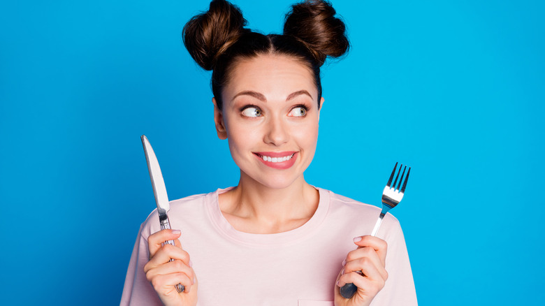 woman who is ready to eat with fork and knife