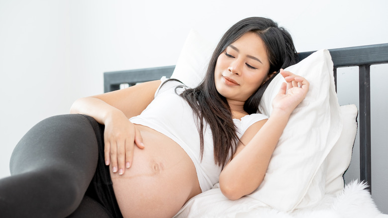 woman lying down touching pregnant belly