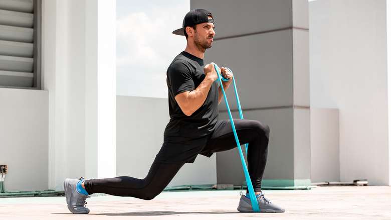 Athletic man doing lunges with resistance bands