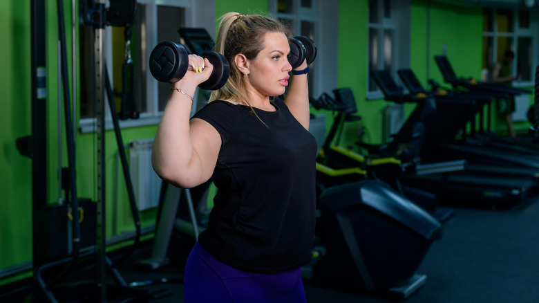 woman performing dumbbell military presses