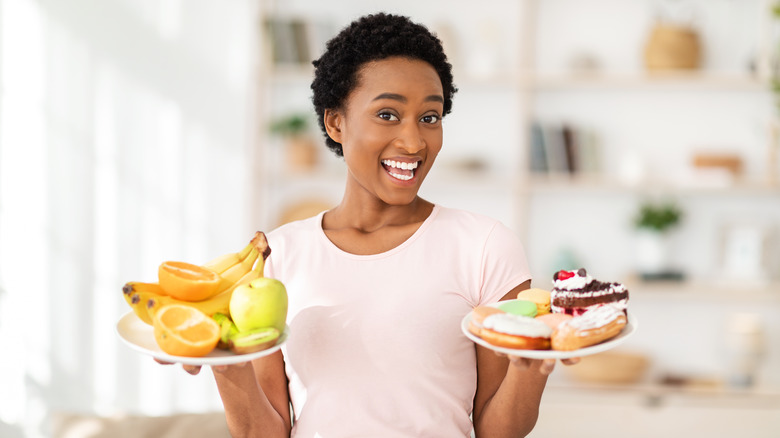 Woman holding plates of fruit and sweets