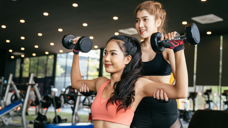 Woman lifting weights with trainer