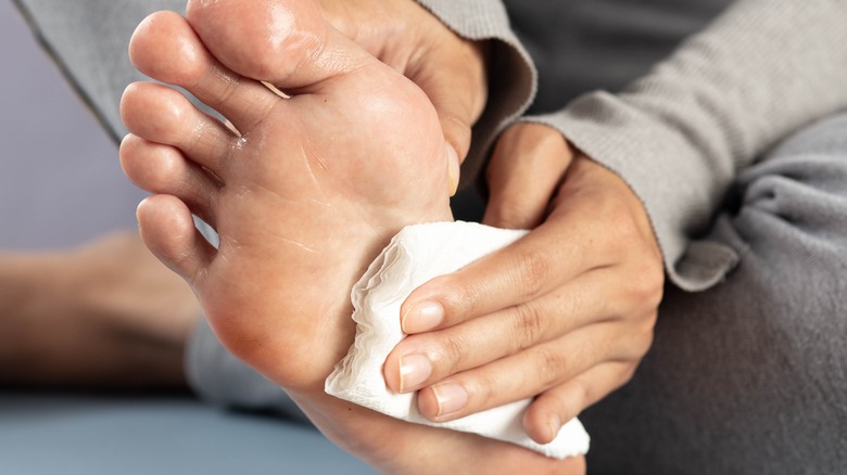 woman wiping excess perspiration from foot