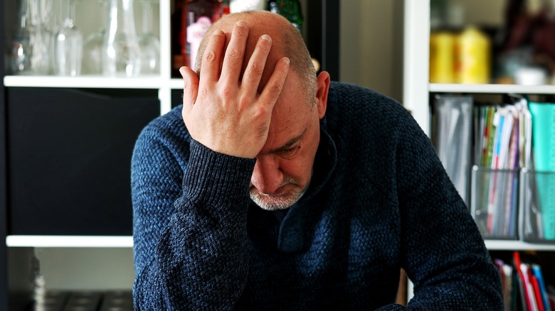 man sadly holding his head