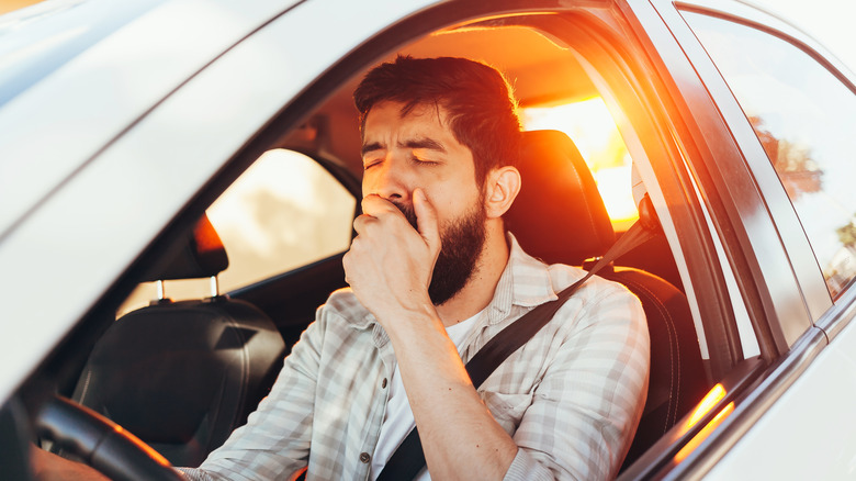 man yawning driving car