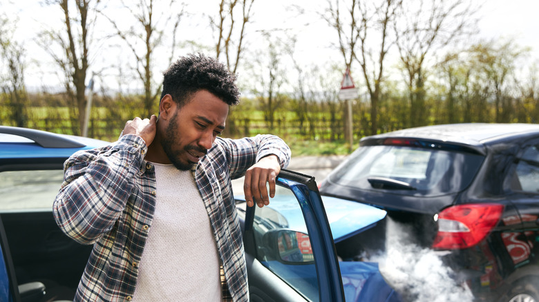 Man getting out of car holding neck