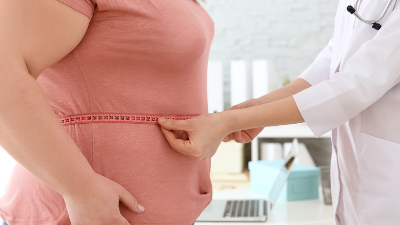 doctor measuring woman's stomach with tape