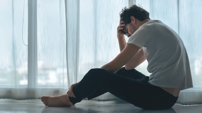 sad bespectacled man holding head