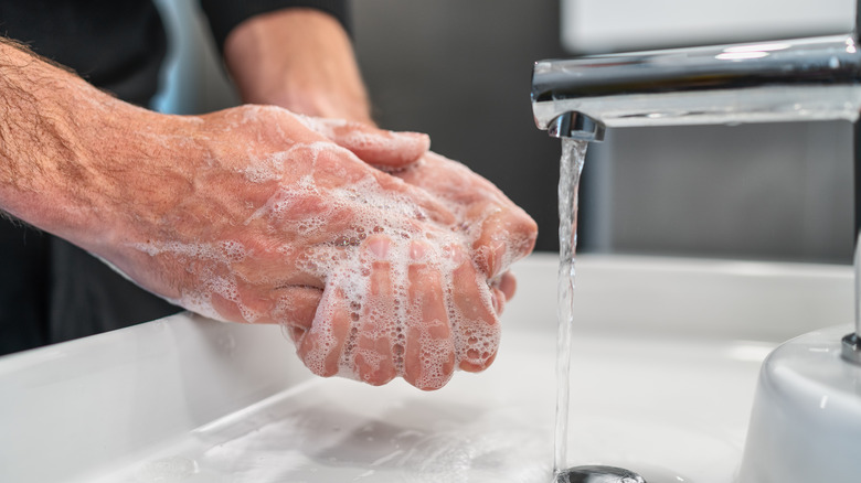 soapy hands being washed at sink