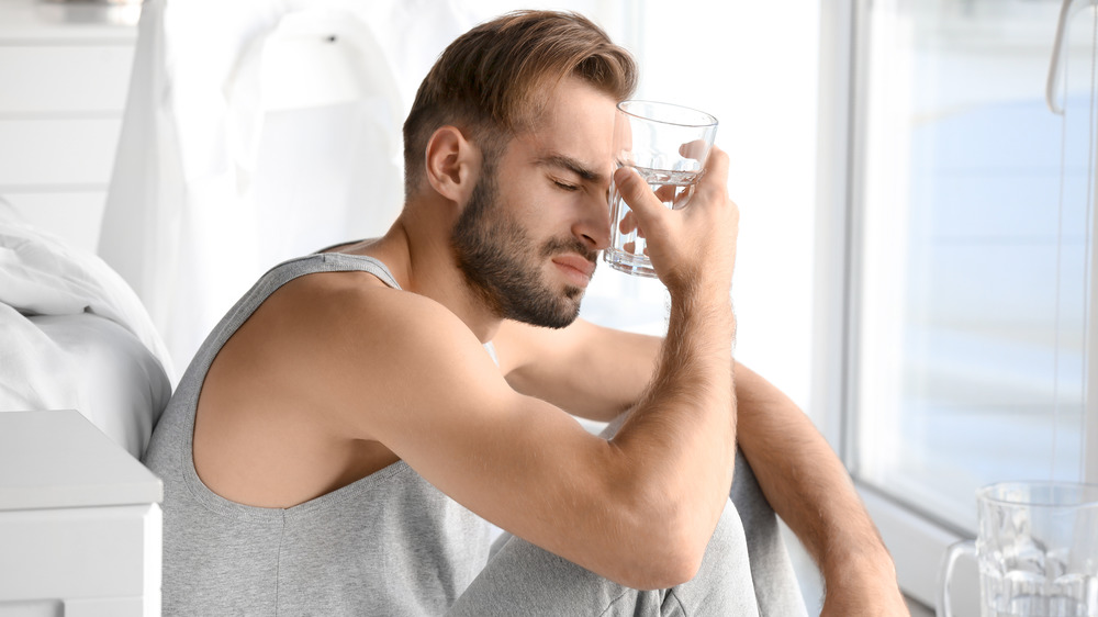 Man with hangover holding water