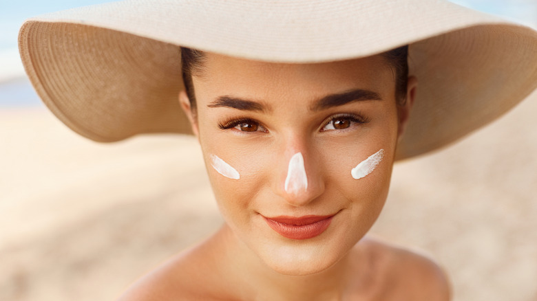 Smiling woman wearing sun hat and sunscreen
