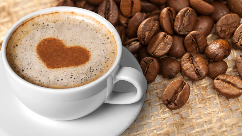 cup of coffee with a heart surrounded by coffee beans