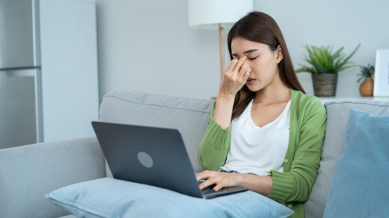 A woman is on her computer and tired