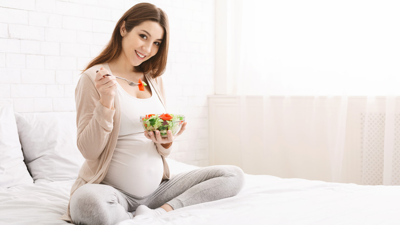 smiling pregnant woman eating salad