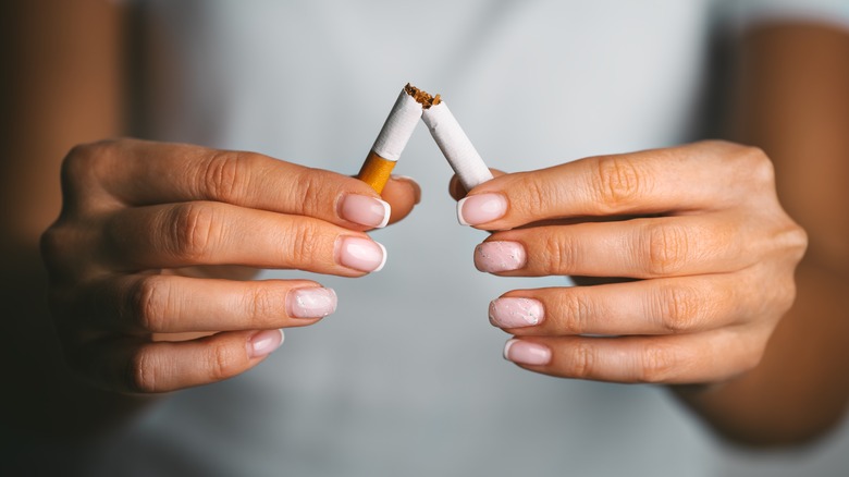 A woman snaps a cigarette in half