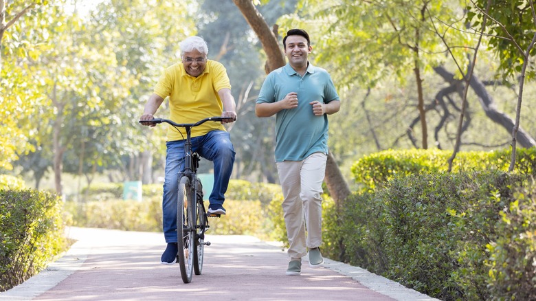 Two men bicycling and jogging outdoors