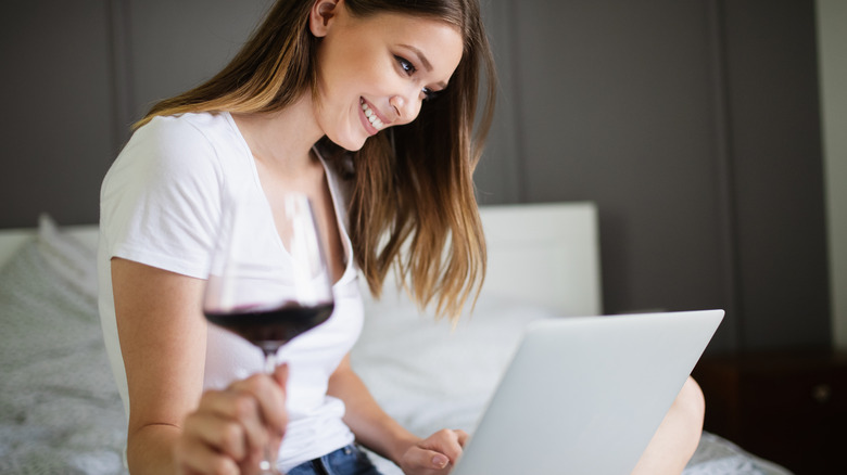 women drinking wine in bed with laptop