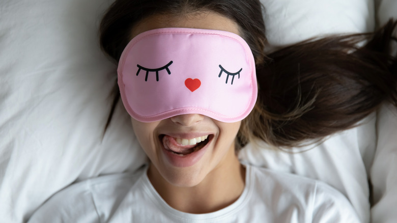 happy girl in bed with pink eye covering 