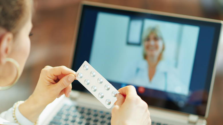 Woman doing telehealth visit holding blister pack