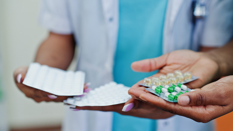 Two people holding four different medications