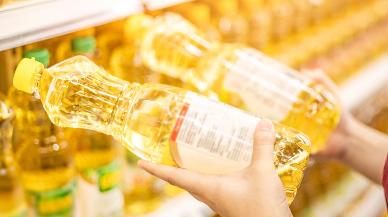 person holding two bottles of oil