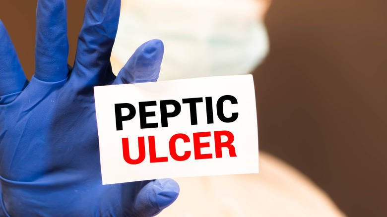 Doctor holding up card with PEPTIC ULCER written on it