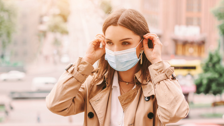 A woman puts on a face mask