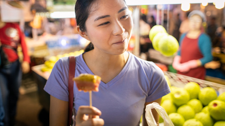 A happy woman eating a piece of guava fruit