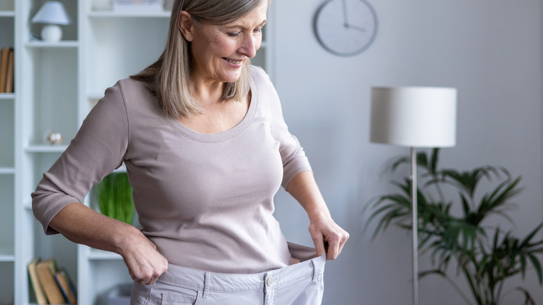 An older woman stretching out pants that are too big