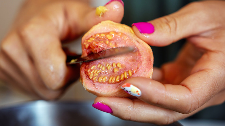 Close-up shot of a woman's hands cutting a guava fruit