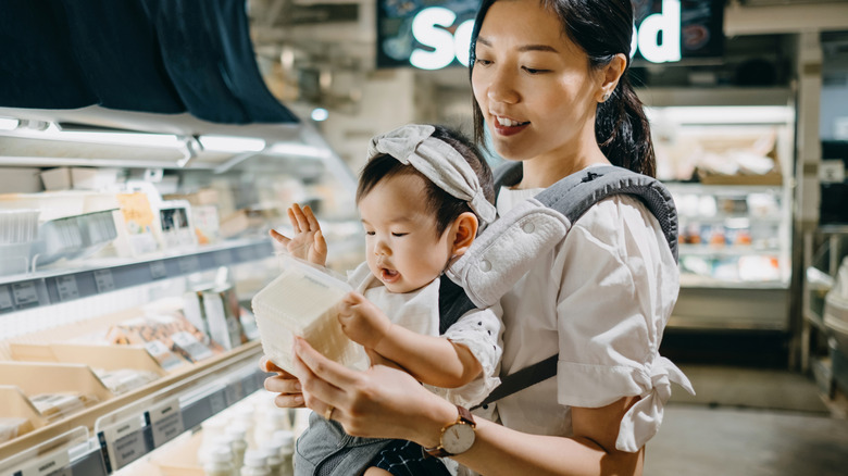 A young mother with a baby looking at tofu